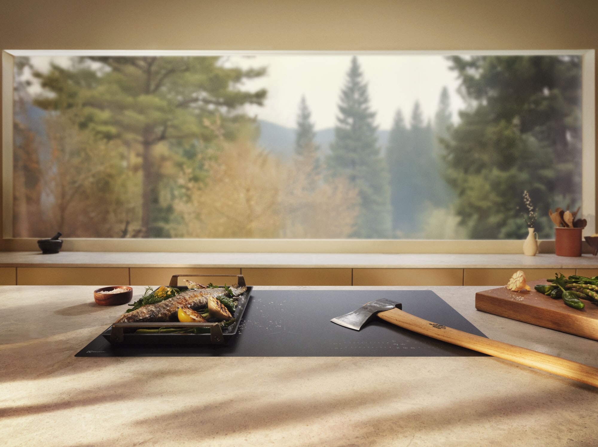 Eine Küche mit mit wunderschönem Ausblick auf einen Wald. Im Vordergrund ein Induktionskochfeld von Electrolux, auf dem ein angerichtetes Gericht steht.