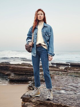 Frau in Jeans auf einem Felsen