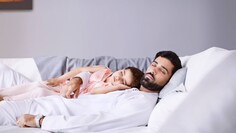 Ein Elternteil, das mit einem Kind in einem kühlen und ruhigen Zuhause schläft