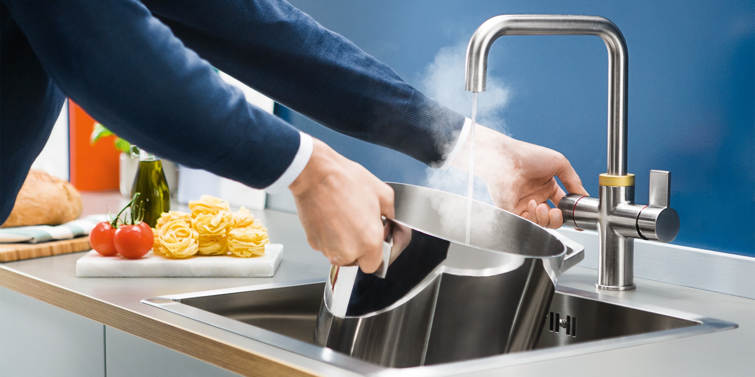 Ein Mann, der einen Topf mit Heißwasser aus der QuickSource Armatur füllt