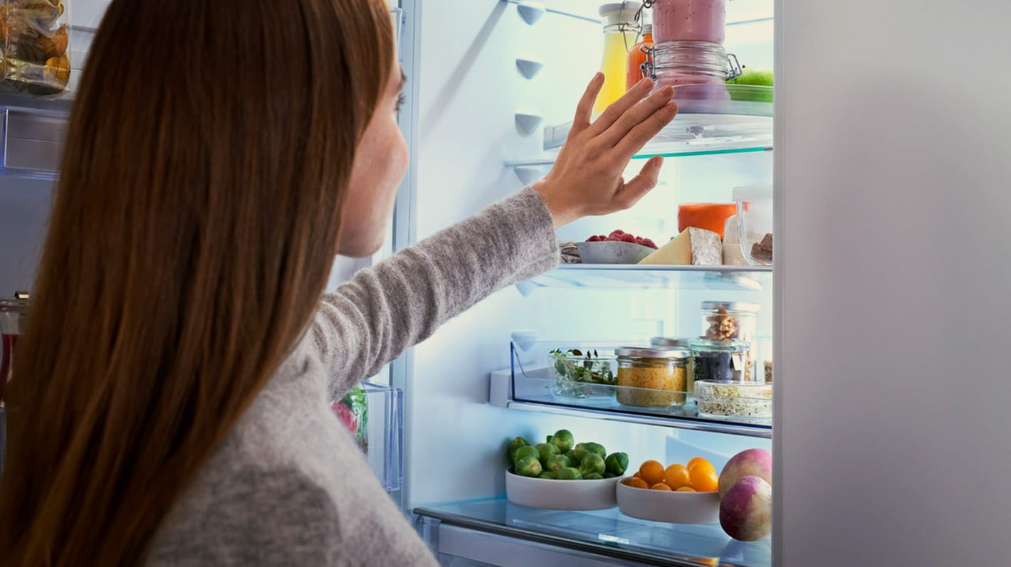 Kvinna som organiserar i kylskåpet