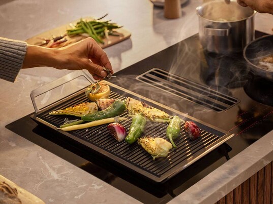 Kochfeld mit Plancha-Grillplatte und Gemüsesorten darauf
