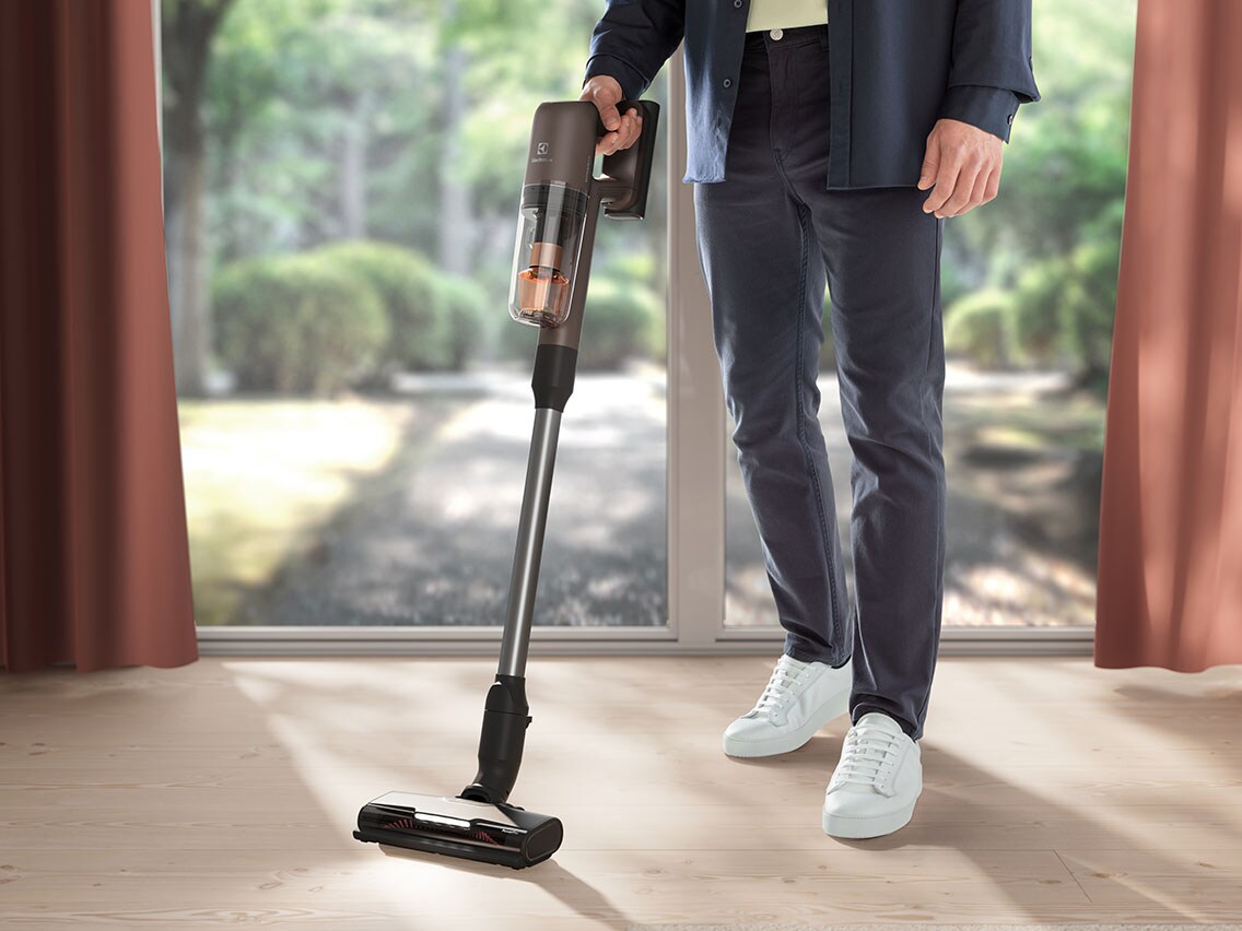 Ein Mann mit einem kabellosen Staubsauger in der Hand