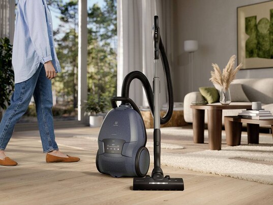 Aspirateur traîneau dans un salon et une dame à côté