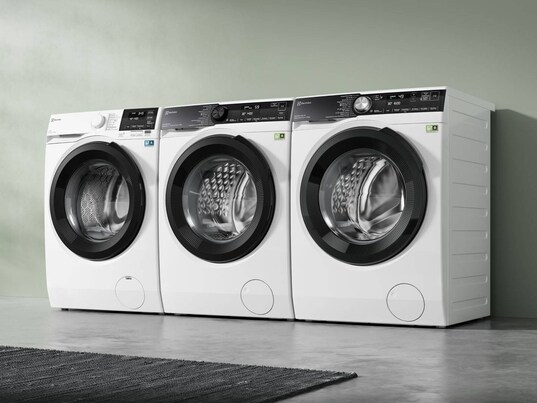Drei Wäschepflege-Modelle nebeneinander vor einer grünen Wand