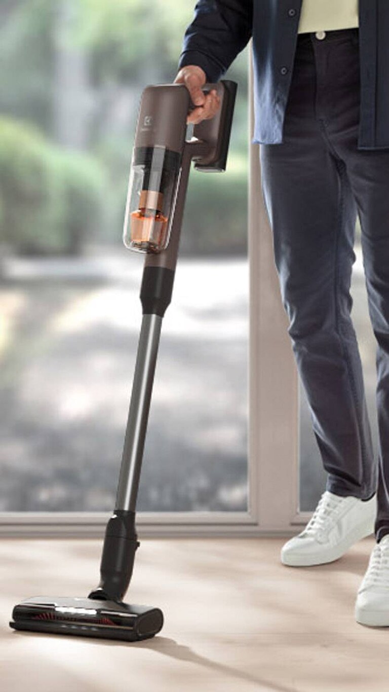 Mann mit einem Electrolux 700 Staubsauger in der Hand im Wohnzimmer
